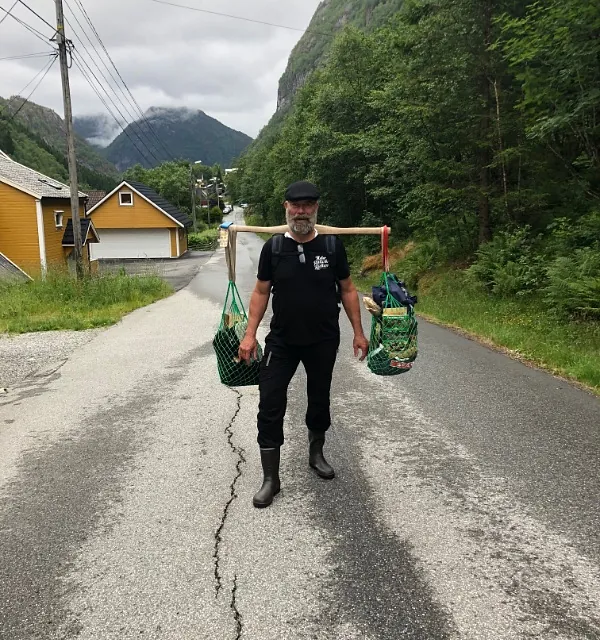Mann bærer poser med bærebjelke