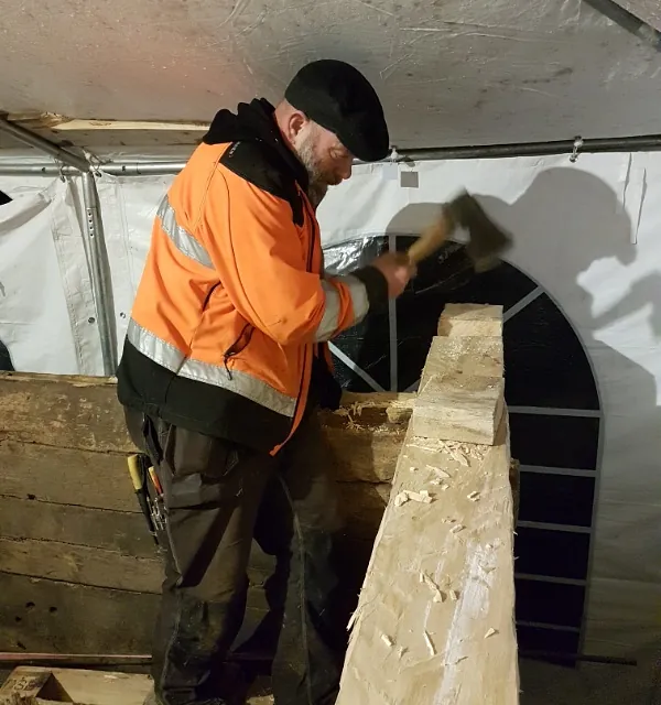 Mann i oransje refleksjakke hugger tre
