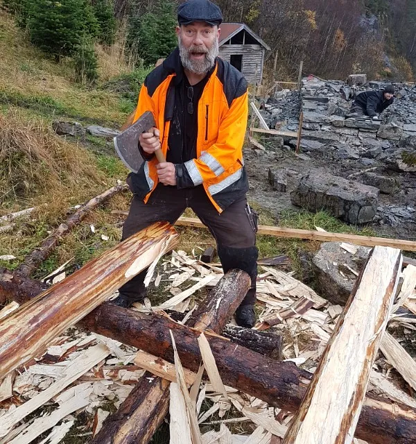 Mann i oransje refleksjakke hugger tre